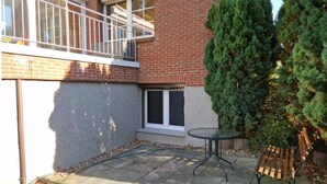 A brick building with a small patio area, a wooden bench, and a potted plant. - FeWo SN-Zippendorf with sauna, close to the beach and 4 km to the Citty (Schwerin)