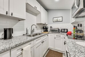 A modern kitchen with white cabinets, granite countertops, and stainless steel appliances. - Cozy Jacksonville Cottage, Walkable Location! (Jacksonville)
