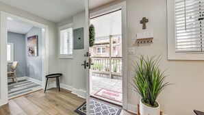 A modern interior with a wooden floor, a door leading to a balcony, a potted plant, and a welcome mat. - Cozy Jacksonville Cottage, Walkable Location! (Jacksonville)