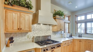 A kitchen with wooden cabinets, a stainless steel stove, and a window providing natural light.