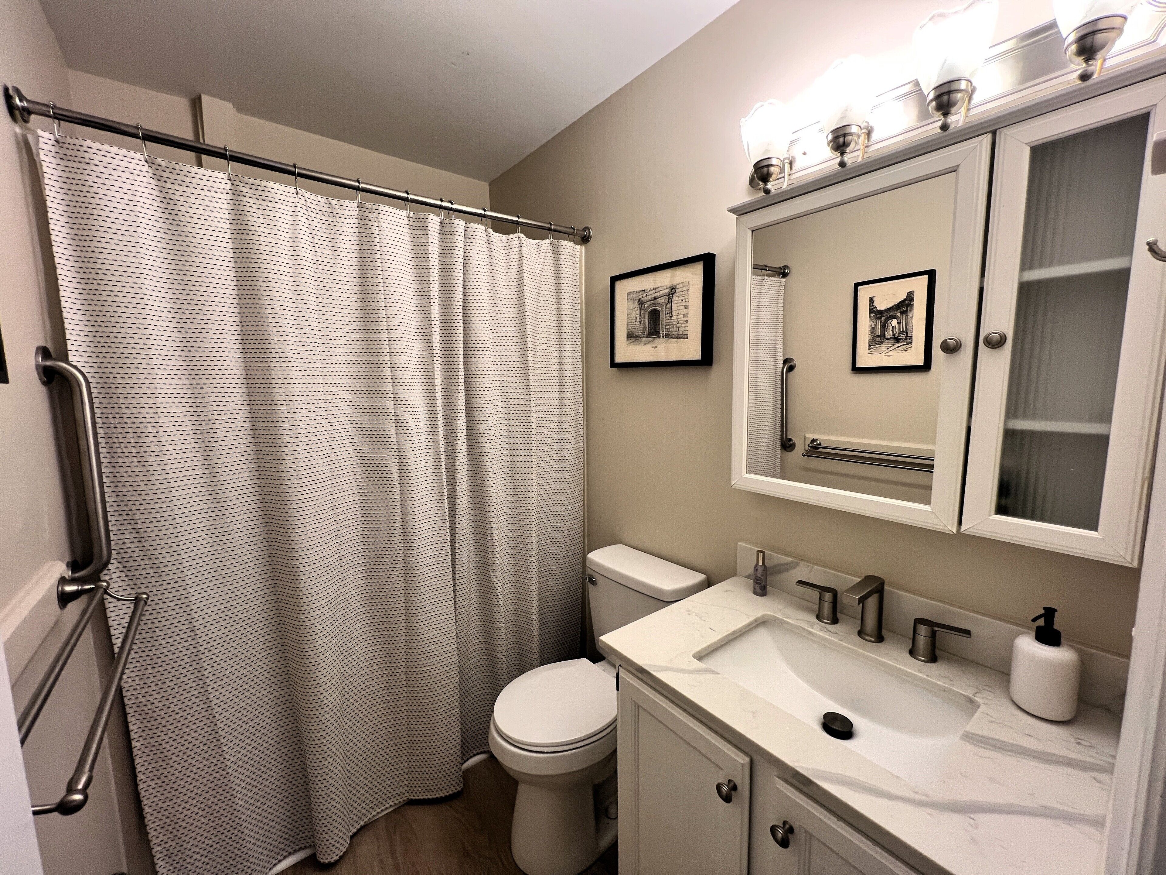 Un baño con cortina de ducha, inodoro, lavabo y espejo sobre el lavabo.