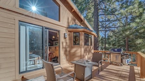 A wooden deck with outdoor furniture, a grill, and a large window overlooking a forest. - Home 1 Mi to Downhill Ski Resort: Bring Your Pets! (Truckee)