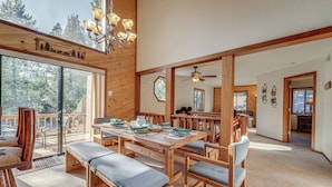 A spacious dining area with wooden furniture and a large table, connected to a balcony with a view of trees. - Home 1 Mi to Downhill Ski Resort: Bring Your Pets! (Truckee)