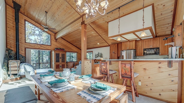 A spacious wooden cabin with a dining area set for a meal, a kitchen with modern appliances, and large windows offering views of the surrounding forest. - Home 1 Mi to Downhill Ski Resort: Bring Your Pets! (Truckee)