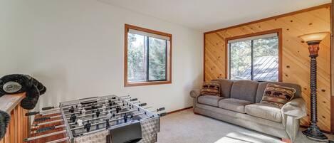 A cozy living room with a foosball table, a sofa with patterned cushions, and a lamp.