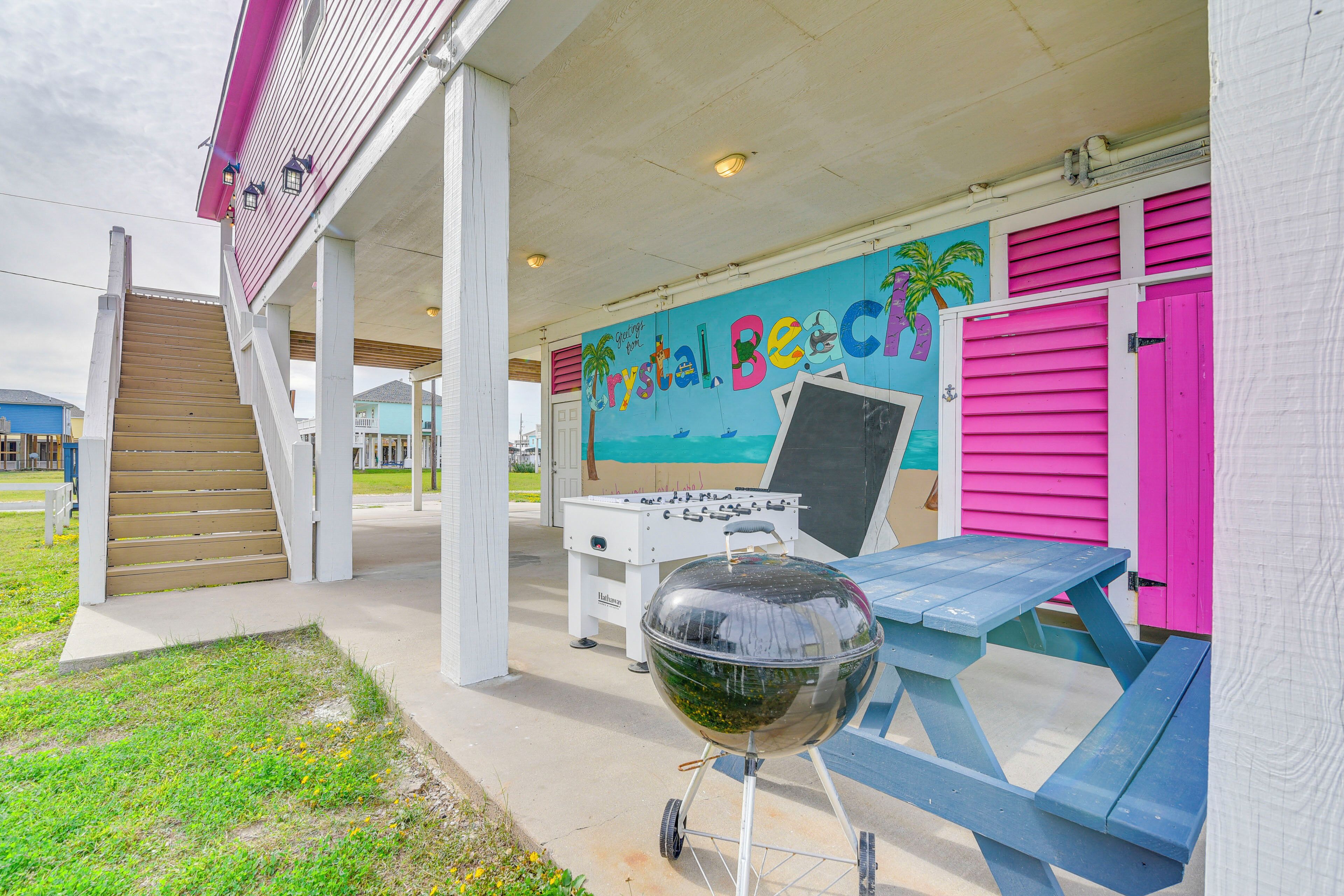 A covered outdoor area with a barbecue grill, picnic table, and a mural of a beach scene.