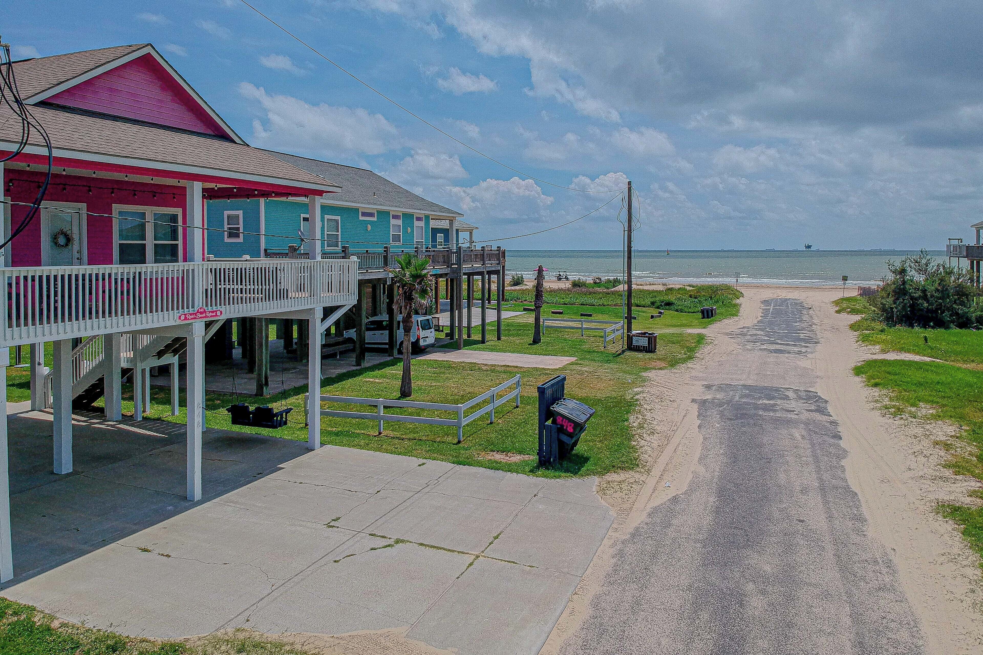 A coastal property with a pink and blue building, a covered porch, and a view of the ocean.