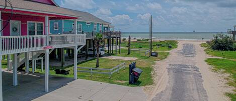 A coastal property with a pink and blue building, a covered porch, and a view of the ocean.