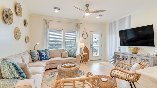 A spacious living room with a sofa, wicker chairs, a coffee table, and a flat-screen TV. - Steps to Beach: Pet-friendly Crystal Beach Home (Port Bolivar)