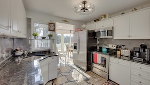 A modern kitchen with white cabinets, a granite countertop, a stainless steel refrigerator, a microwave, a stove, and a coffee maker. - 2 Mi to Hersheypark: Group Getaway w/ Deck (Hummelstown)