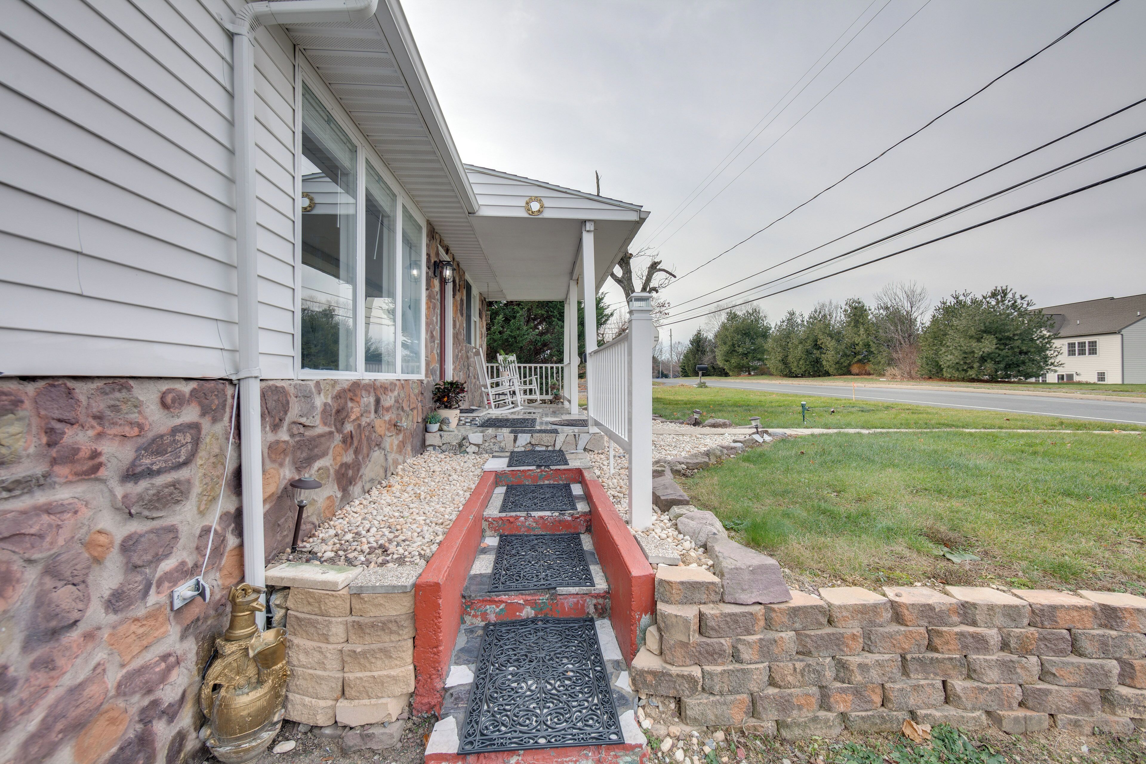 A house with a stone foundation, a porch with steps, and a small garden area.