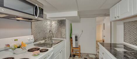 A modern kitchen with a microwave, stove, and sink.