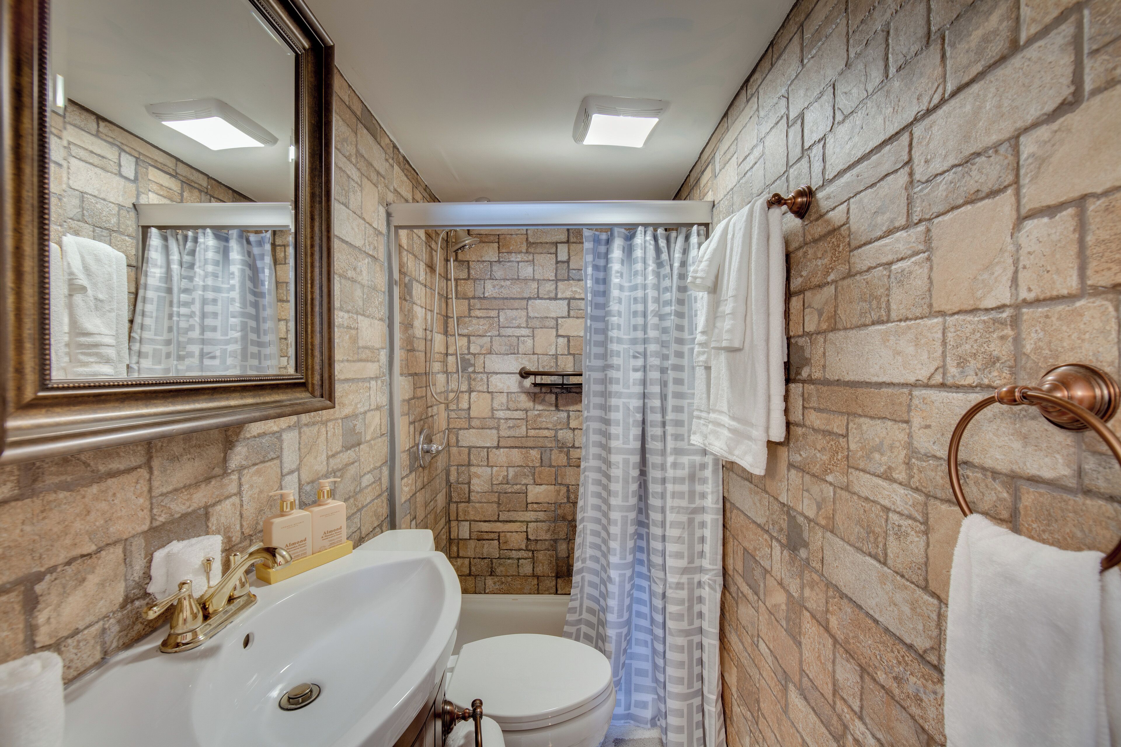 A bathroom with a white sink, a toilet, and a shower with a patterned curtain.