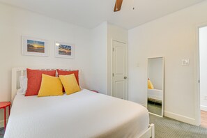 A bedroom with a bed, pillows, a nightstand, a mirror, and two framed pictures on the wall. - Galveston Vacation Rental Near Cruise Terminals! (Galveston)