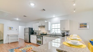 Una cocina moderna con armarios blancos, electrodomésticos de acero inoxidable y encimera de granito.