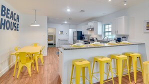 Una cocina moderna con armarios blancos, encimera de granito y taburetes amarillos.