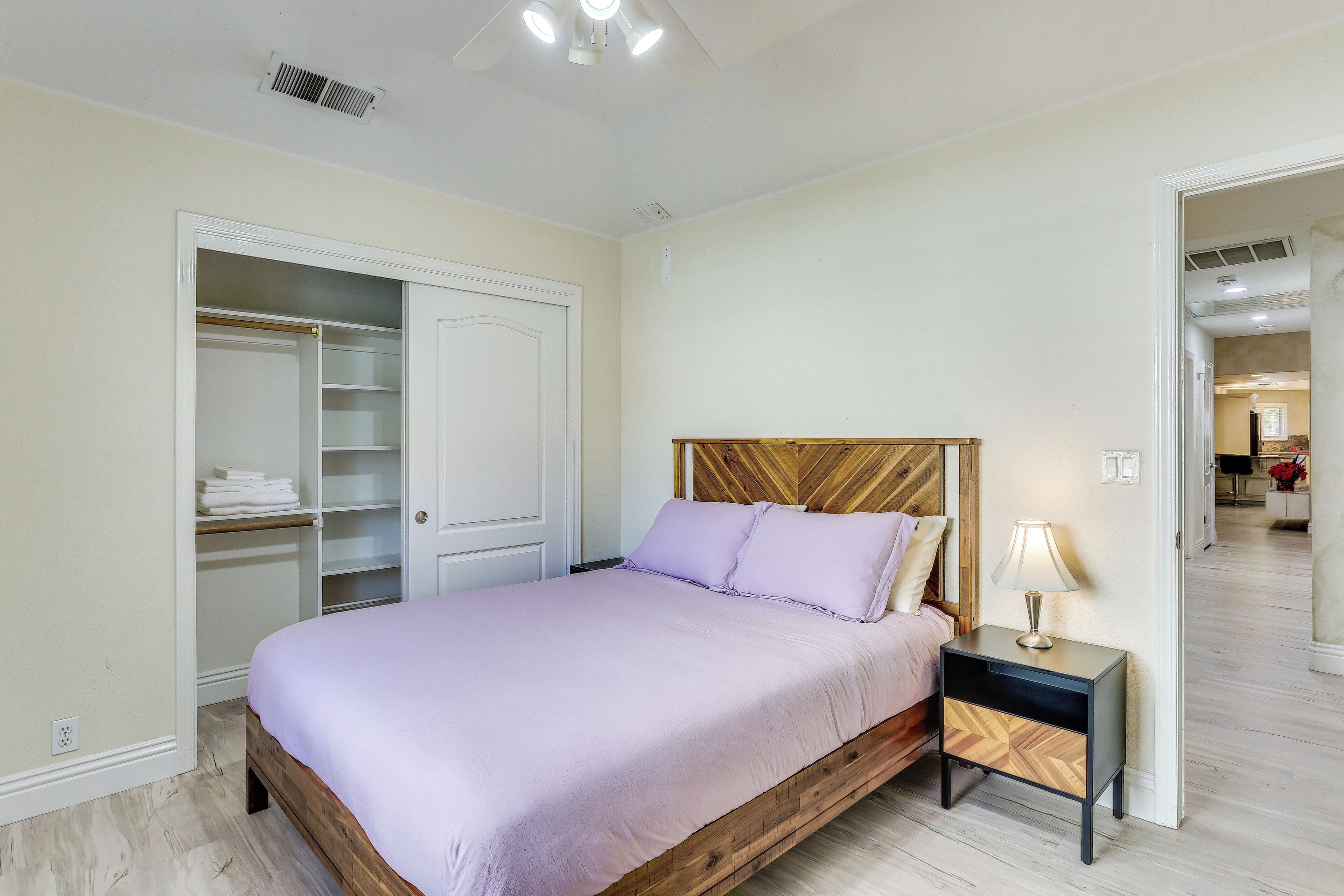 A bedroom with a bed, nightstand, wardrobe, and a door leading to another room.