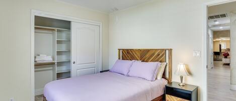 A bedroom with a bed, nightstand, wardrobe, and a door leading to another room.