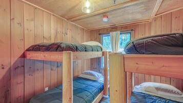 Dormitorio con literas, paredes de madera y una ventana.