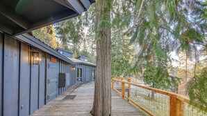 A wooden deck with a railing, a large tree, and a building with a blue facade.
