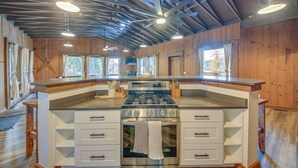 A modern kitchen with a central island, stainless steel appliances, and wooden accents.