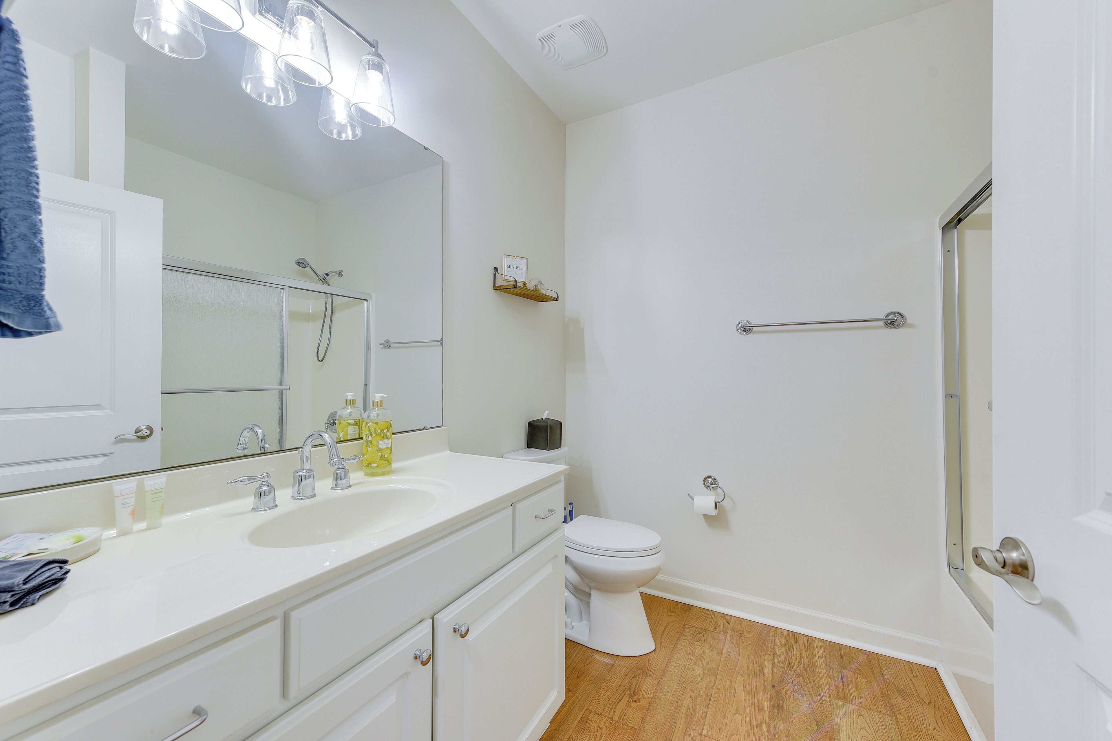 Un baño moderno con lavamanos, espejo y retrete blancos.