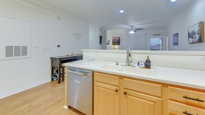 A modern kitchen with white countertops, wooden cabinets, a dishwasher, and a ceiling fan. - Crow Creek Golf Club Condo w/ Community Perks! (Calabash)