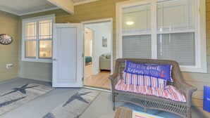 A porch with a wicker chair, a door leading to a room, and a welcome mat. - Crow Creek Golf Club Condo w/ Community Perks! (Calabash)