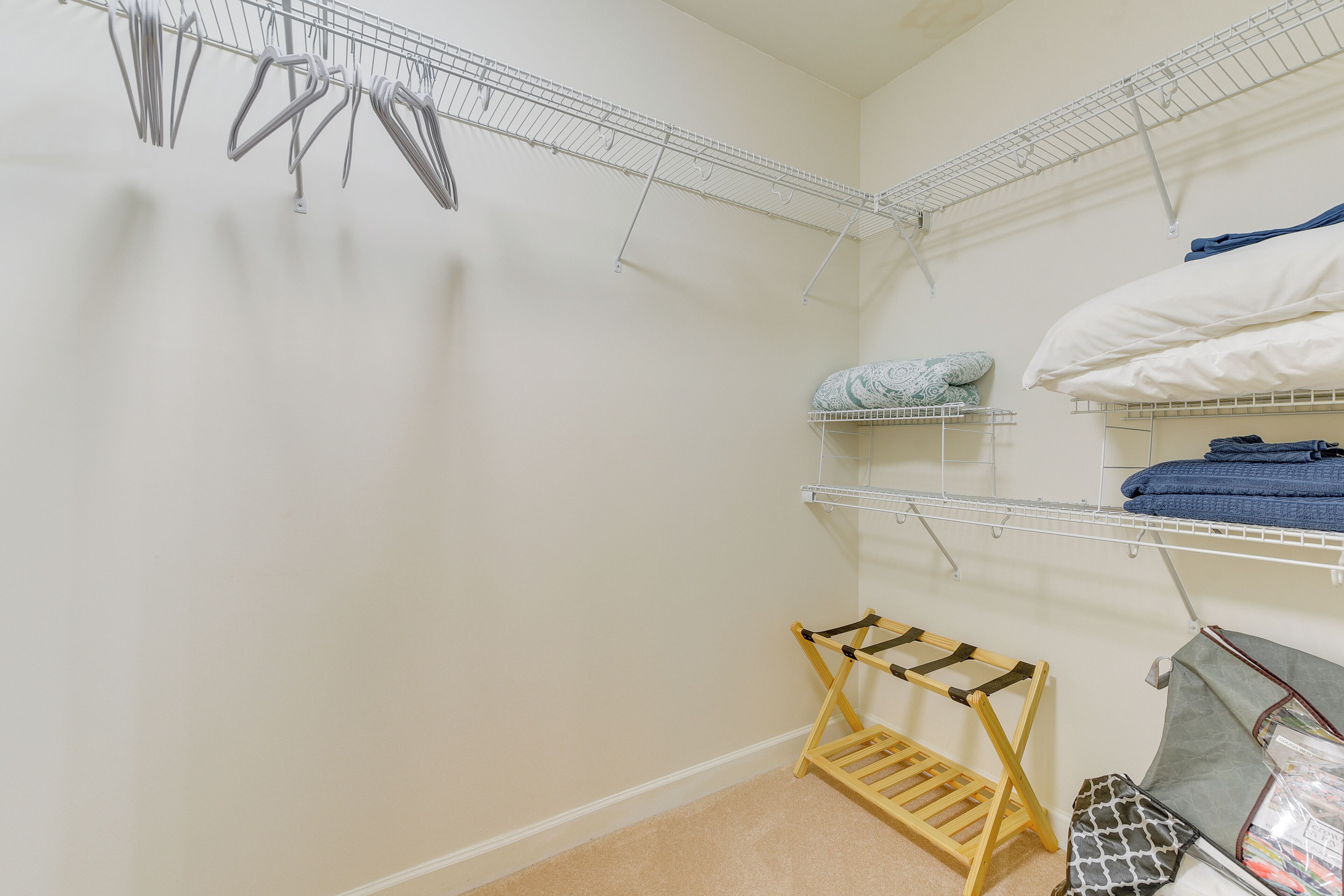 A closet with metal shelves, a wooden drying rack, and folded clothes.