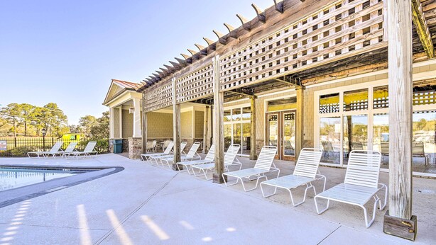 A poolside area with lounge chairs and a pergola structure. - Crow Creek Golf Club Condo w/ Community Perks! (Calabash)