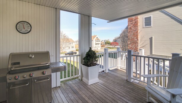A covered outdoor area with a grill, a clock, and a potted plant. - Scituate Vacation Rental - Walk to the Beach! (Scituate)