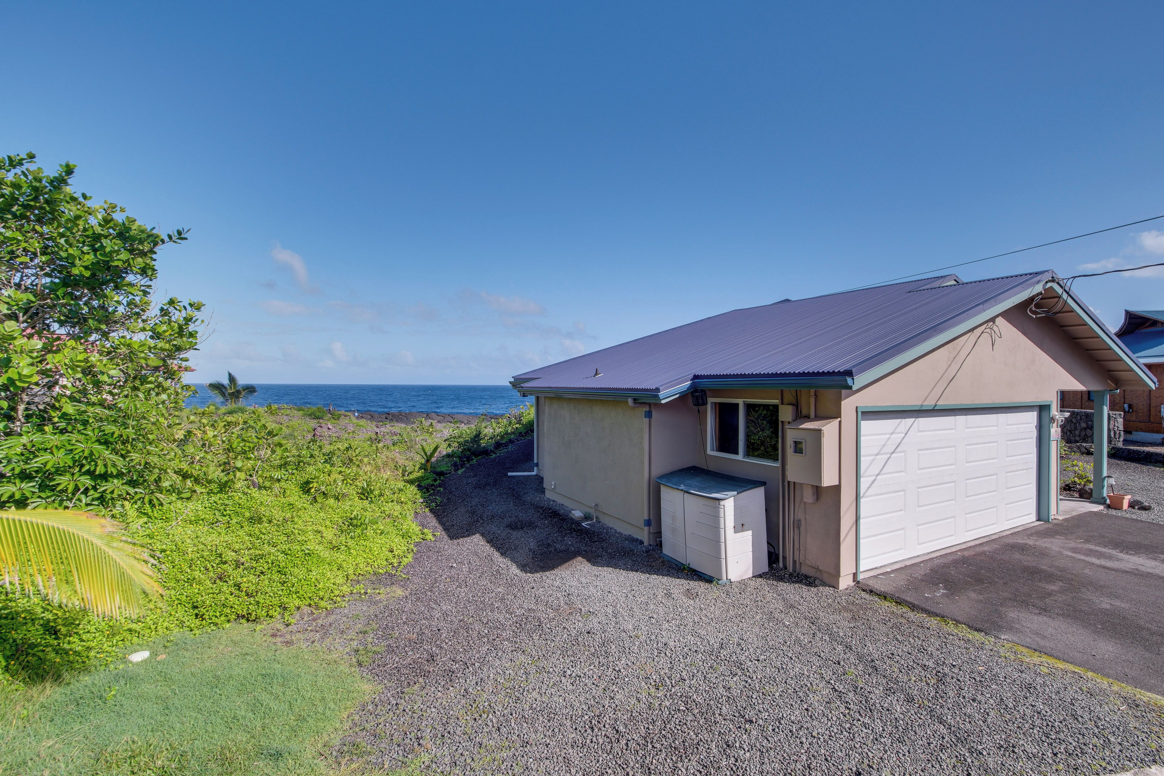A single-story house with a garage, a small attached shed, and a gravel driveway.