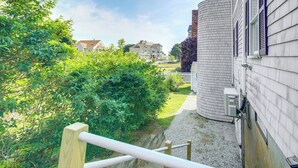 A residential area with a pathway leading to a house with a cylindrical water tank attached to the side. - Pet-friendly Garden Studio ~ 25 Mi to Boston! (Scituate)