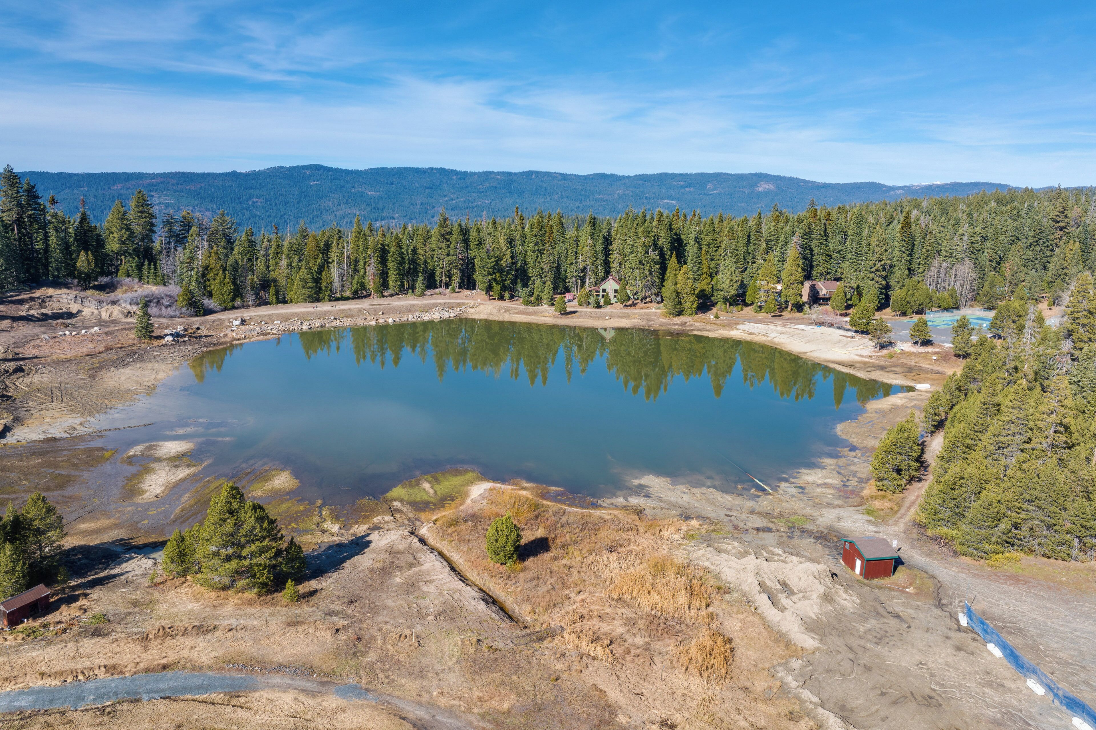Ein großer, ruhiger See, umgeben von dichten Wäldern und Bergen.