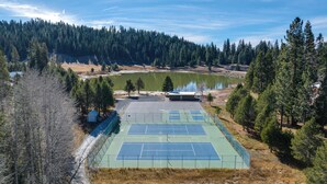Una cancha de tenis al aire libre rodeada de árboles y un lago.
