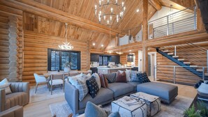 A spacious log cabin interior with a living area, kitchen, and a staircase leading to an upper level. - Ogden's Fancy Fly Luxury Teton Springs Cabin in Victor, ID w/ A/C & Hot Tub (Victor)