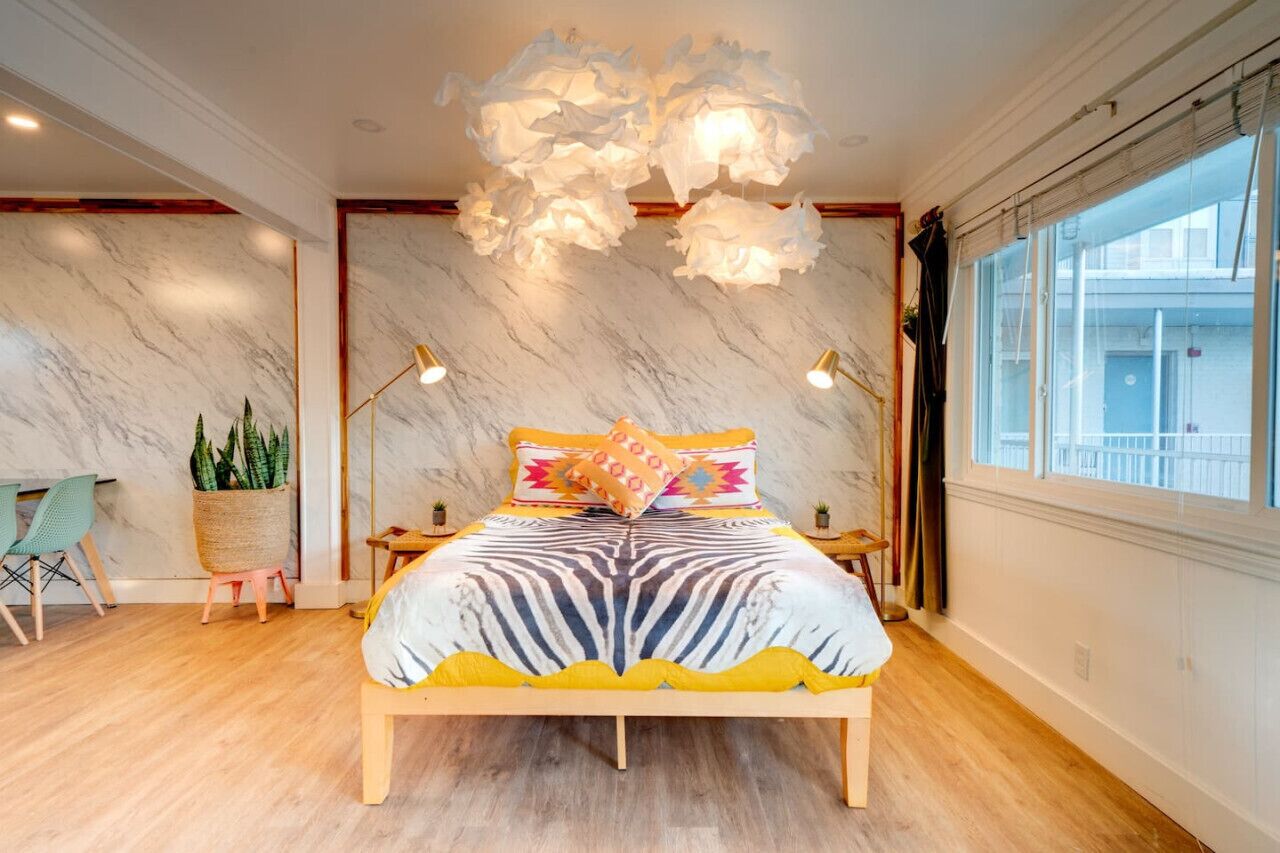 A modern bedroom with a large bed, marble walls, and a view of the city.