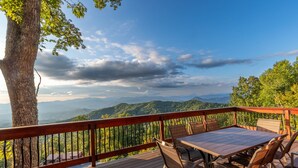 A wooden deck with a table and chairs, overlooking a mountainous landscape. - Majestic Views-Hot Tub - Views - Gas Firepit -4WD-AWD (Whittier)