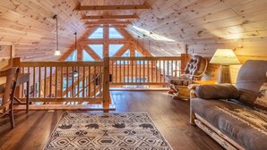 A wooden interior with a high ceiling, a staircase, a sofa, a lamp, and a patterned rug. - Majestic Views-Hot Tub - Views - Gas Firepit -4WD-AWD (Whittier)
