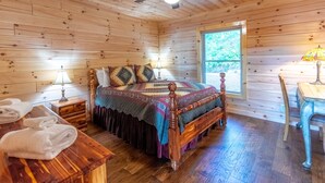A wooden cabin bedroom with a bed, bedside tables, a desk, and a window. - Majestic Views-Hot Tub - Views - Gas Firepit -4WD-AWD (Whittier)