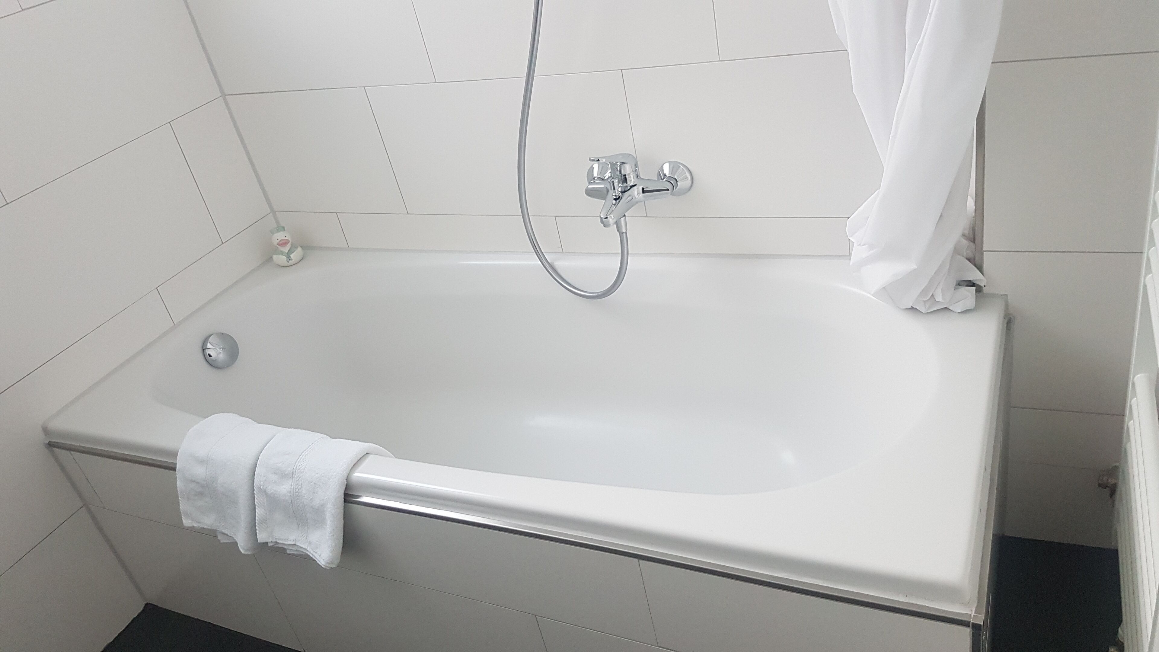 A standard white bathtub with a handheld showerhead and a single faucet.