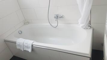 A standard white bathtub with a handheld showerhead and a single faucet.