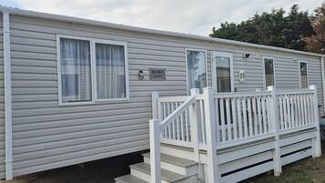 A mobile home with a white exterior, a front porch with a railing, and a nameplate that reads 'RUBY.'