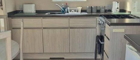 A compact kitchen with a microwave, toaster, sink, and stove.