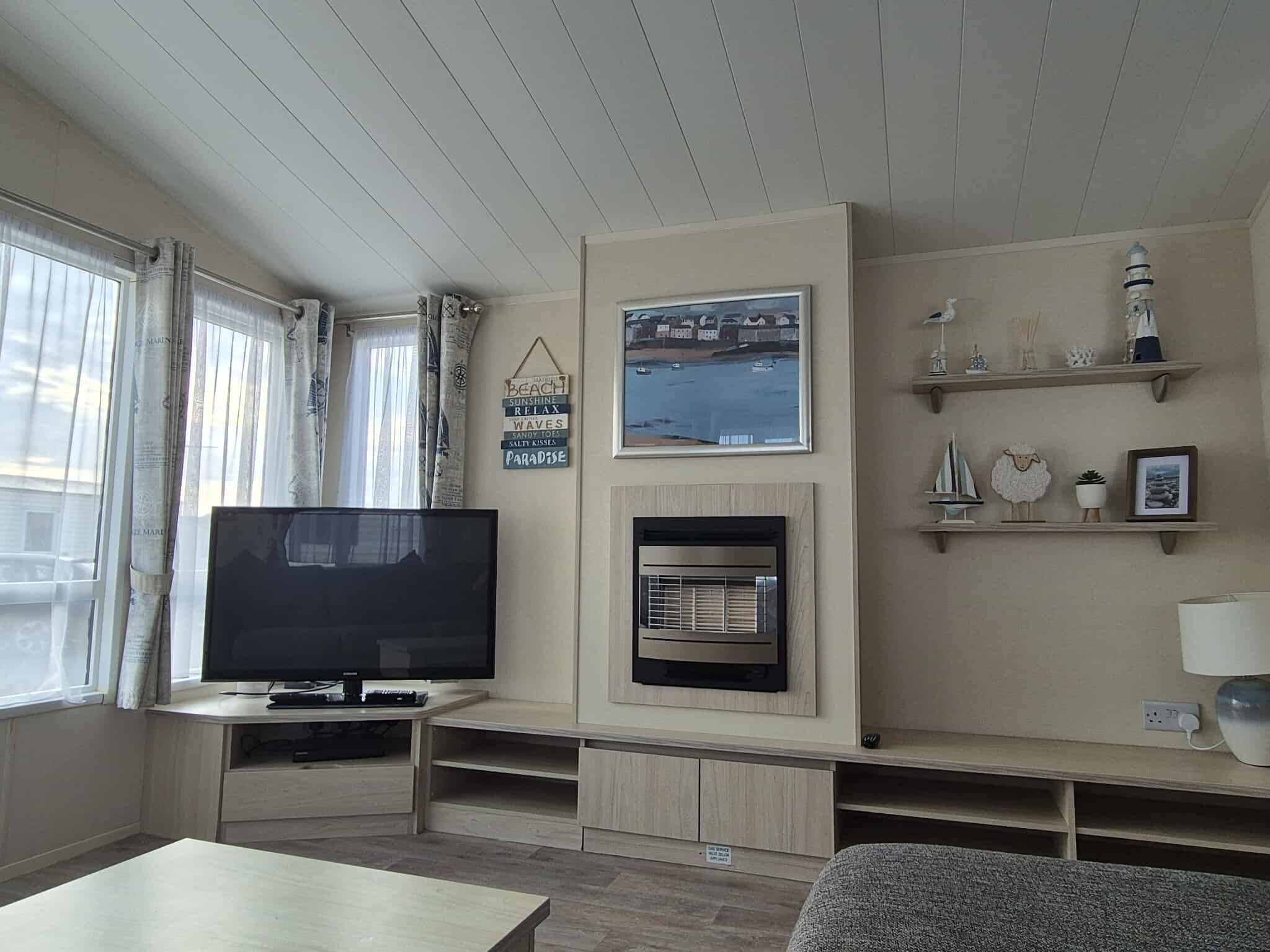 Una sala de estar con televisor de pantalla plana, chimenea y vista al mar.