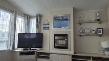 Una sala de estar con televisor de pantalla plana, chimenea y vista al mar.
