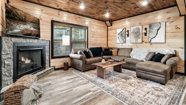 Un salon chaleureux avec une cheminée, des murs en bois et une grande fenêtre.