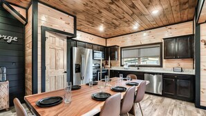 Une cuisine moderne avec un lambris en bois, des appareils électroménagers en acier inoxydable et un coin repas aménagé pour quatre personnes.