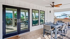 A covered patio with a table and chairs, sliding glass doors, and a ceiling fan. - `Charming Cabin with Private Pool & Spacious Veranda, Steps from Town and Beach!` (Port Aransas)