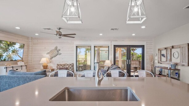 A modern kitchen with a central island, pendant lights, and a ceiling fan. - `Charming Cabin with Private Pool & Spacious Veranda, Steps from Town and Beach!` (Port Aransas)